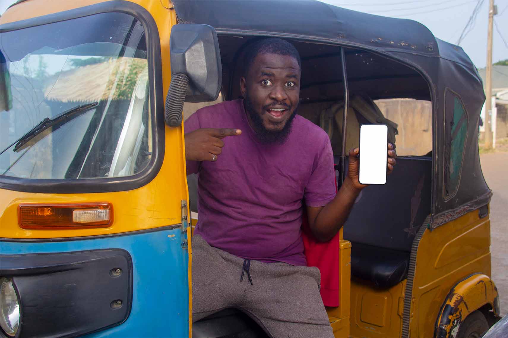 A happy African tricycle rider, also known as Keke or Maruwa, Keke rider, sitting in a tricycle  pointing at his phone